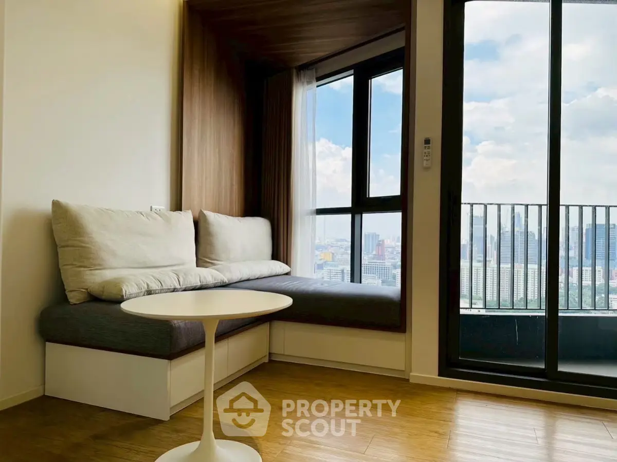 Modern living room with city view and cozy seating area by large window.