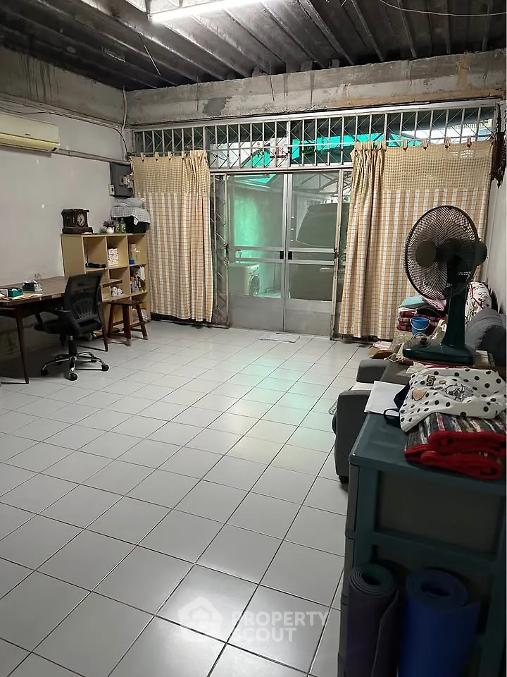 Spacious living room with tiled floor, desk, and fan, ideal for versatile living arrangements.