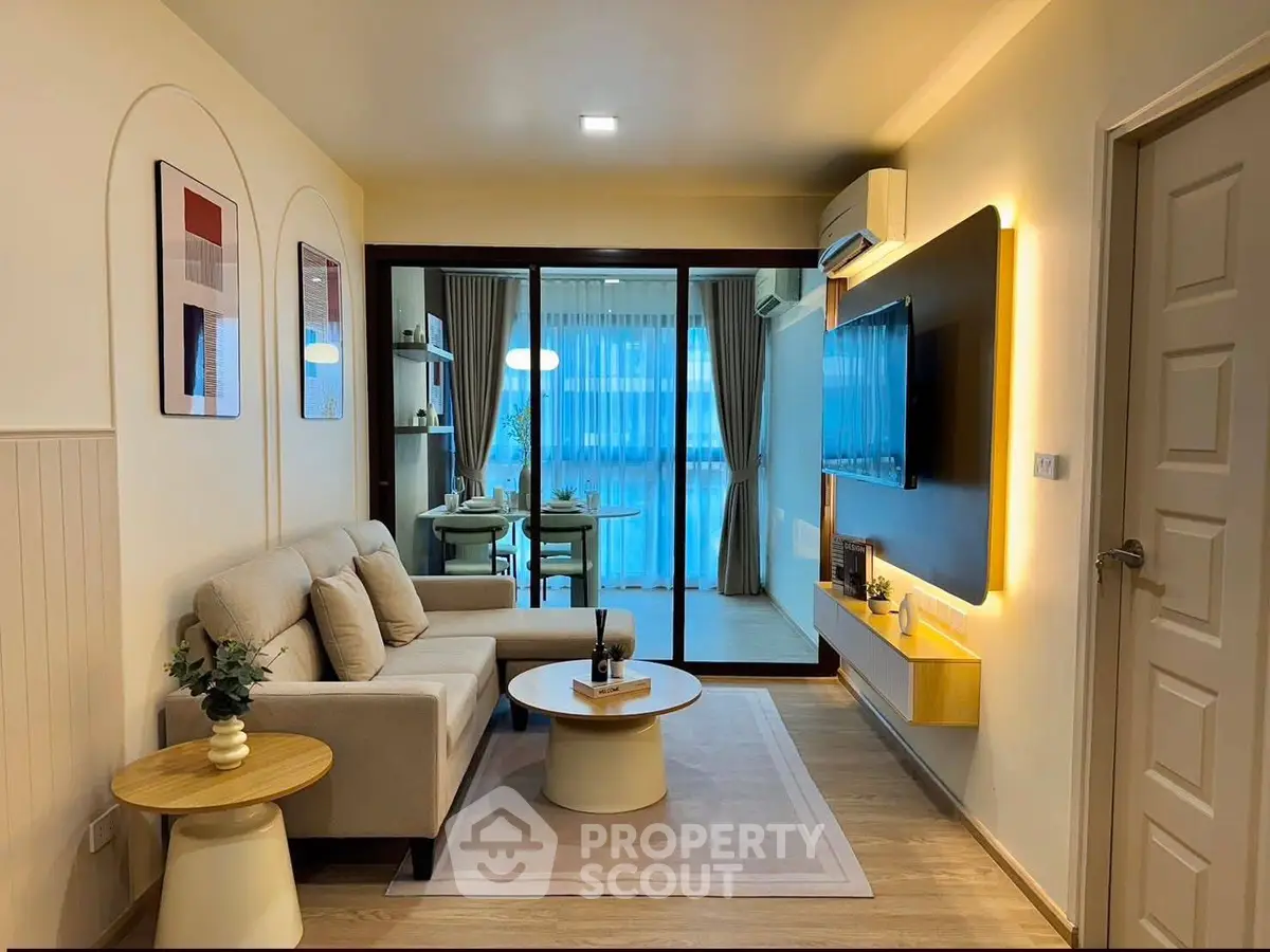 Modern living room with cozy sofa and stylish decor, open to dining area with natural light.