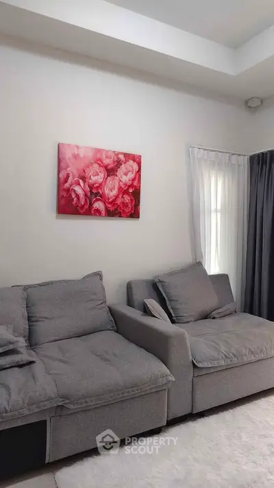 Cozy living room with modern gray sofas and floral wall art, perfect for relaxation.