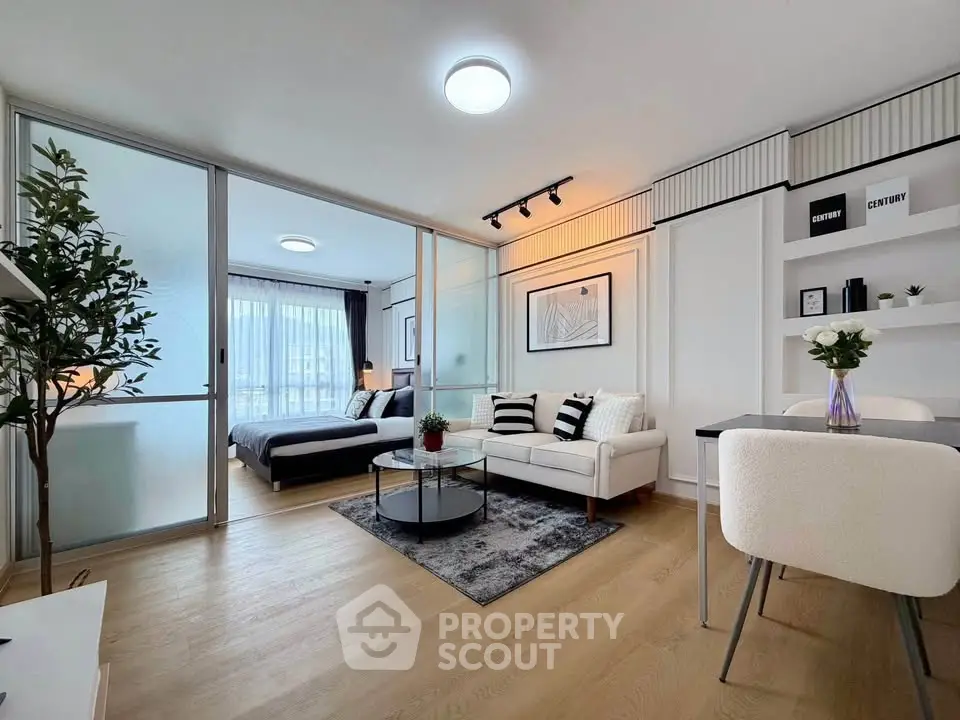 Modern open-plan living room with stylish decor and sliding glass doors leading to a cozy bedroom.