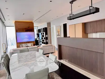 Luxurious open-plan living room with modern kitchen and dining area, featuring sleek design and city views.