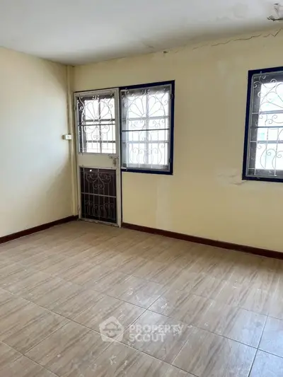 Spacious empty room with tiled flooring and secure windows, ideal for customization.