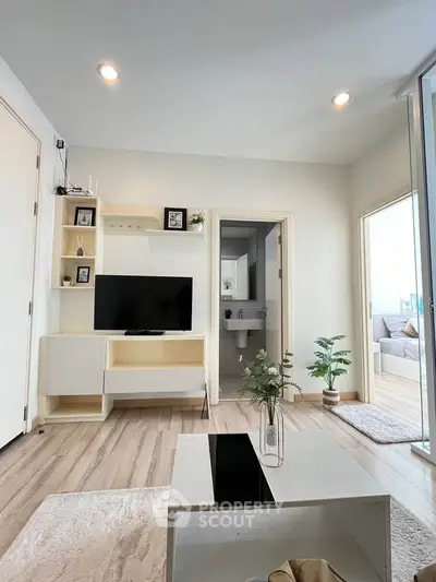 Modern living room with sleek furniture and open layout, featuring a TV and stylish decor.