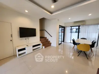 Spacious modern living room with dining area and sleek staircase
