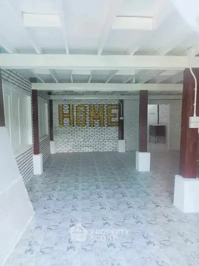 Spacious interior with tiled flooring and decorative brick wall spelling 'HOME'.