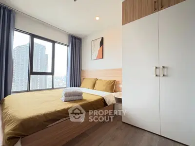 Modern bedroom with large window and city view, featuring stylish decor and ample storage space.