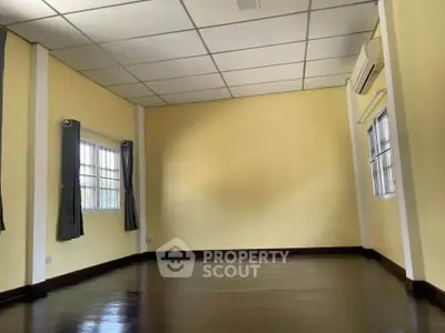 Spacious empty room with polished wooden floors and large windows, perfect for customization.