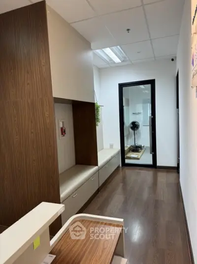 Modern office hallway with wooden flooring and glass door