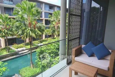 Luxurious balcony view overlooking lush garden and pool in modern apartment complex.
