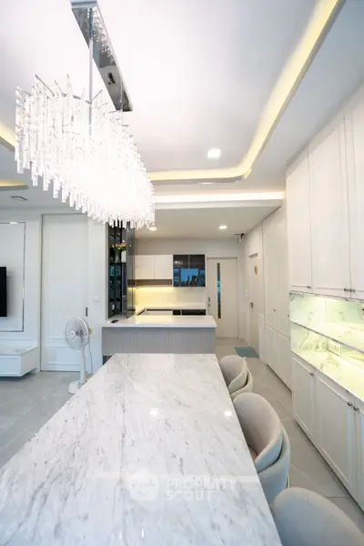 Luxurious modern kitchen with marble countertops and elegant chandelier lighting.