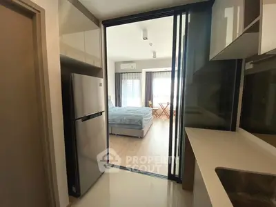 Modern apartment with sleek kitchen and cozy bedroom, featuring sliding glass doors and natural light.