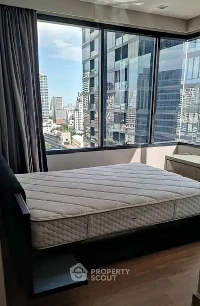 Modern bedroom with large windows offering stunning city views in a high-rise apartment.