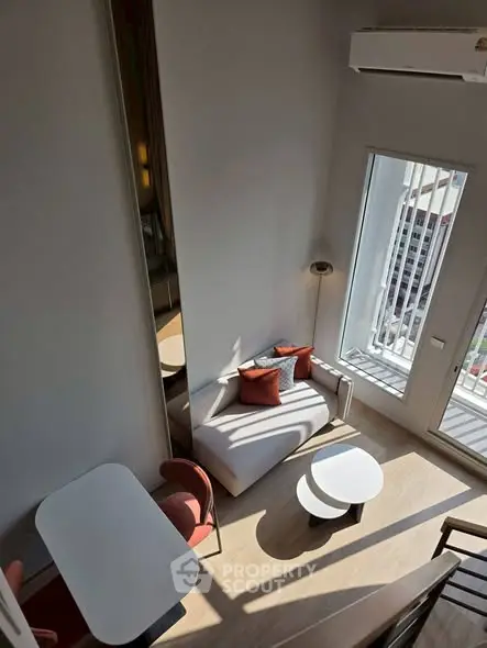 Modern loft apartment with high ceilings and large windows offering city views, featuring stylish furniture and decor.