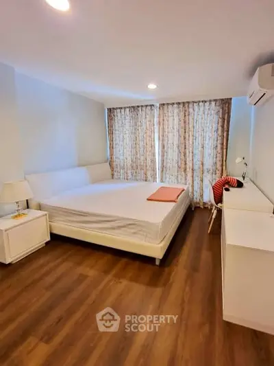 Spacious bedroom with modern decor and large windows in a stylish apartment.
