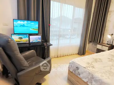 Modern bedroom with work setup, featuring a comfortable chair, dual monitors, and large window view.