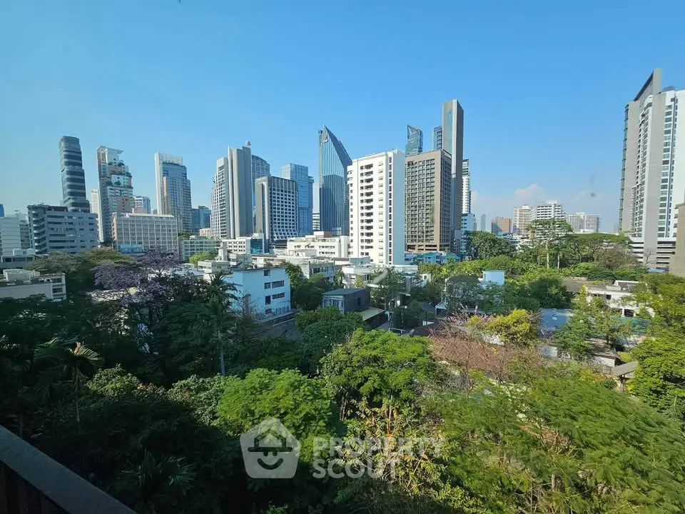 Stunning cityscape view with lush greenery and modern skyscrapers under clear blue sky.
