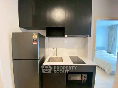 Modern compact kitchen with sleek black cabinets and integrated appliances.