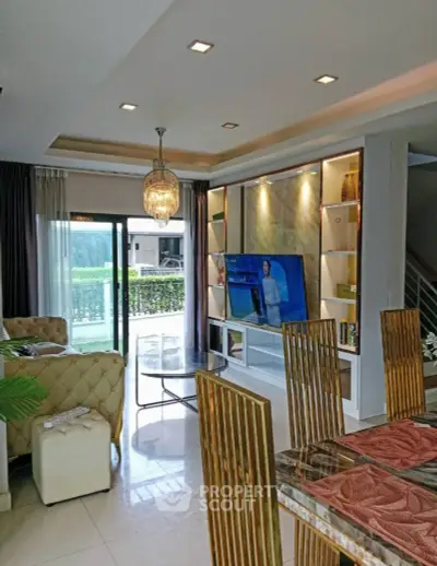 Luxurious living room with elegant decor, large TV, and garden view through sliding glass doors.