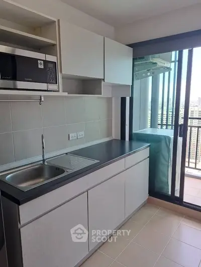 Modern kitchen with sleek cabinetry and balcony view in high-rise apartment.