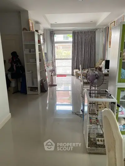 Spacious living room with glossy floors and modern decor, featuring a fan and birdcage for a cozy touch.