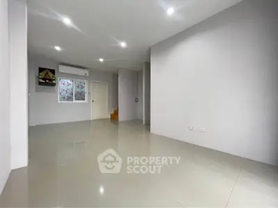 Spacious minimalist living room with glossy tile flooring and modern lighting