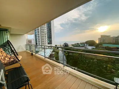 Spacious balcony with stunning ocean view and modern seating area at sunset.