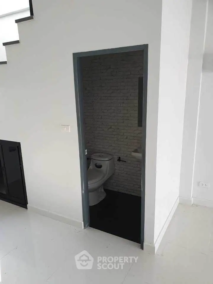 Compact bathroom under staircase with modern design and sleek white tiles