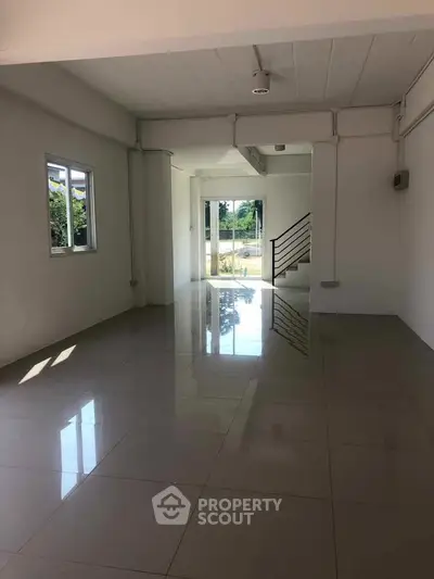 Spacious open-plan living area with large windows and glossy tiled floors, perfect for modern living.