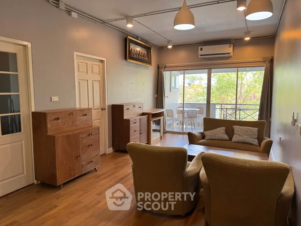 Spacious living room with cozy seating and balcony view in modern apartment.