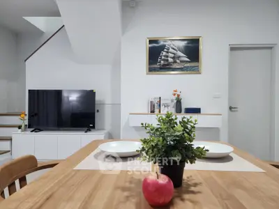Modern living room with stylish decor and sleek furniture, featuring a TV and elegant dining setup.