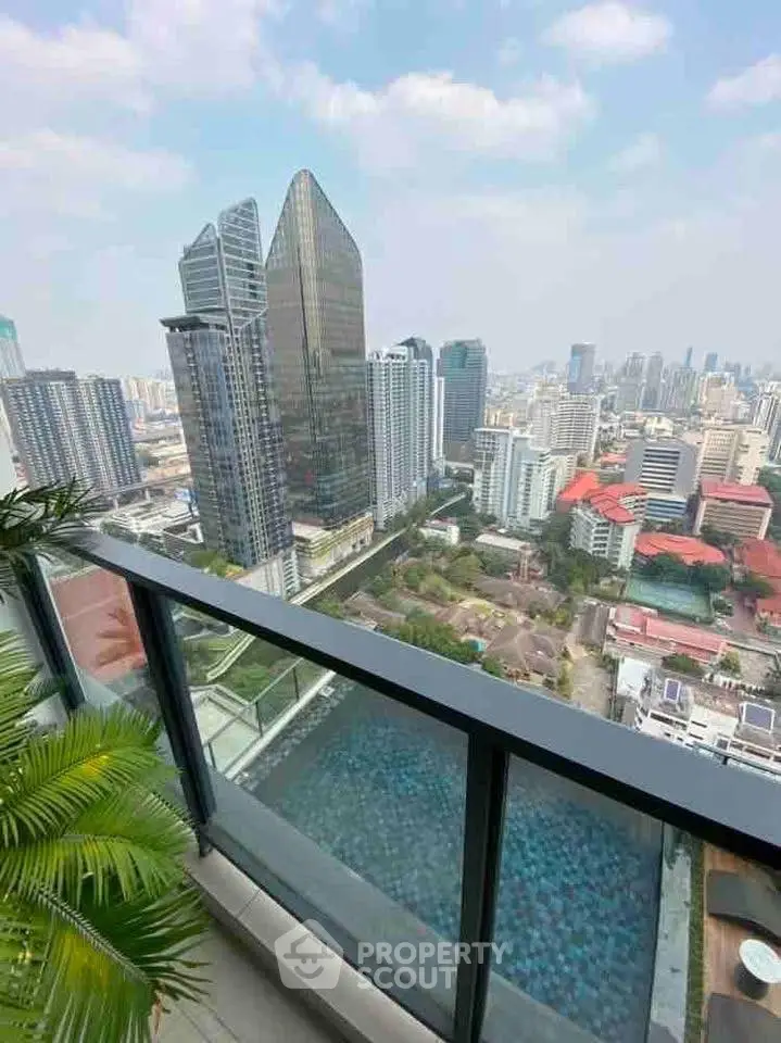 Stunning cityscape view from a high-rise balcony overlooking modern skyscrapers and a pool.