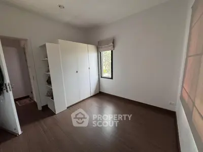 Spacious empty bedroom with wooden flooring and large wardrobe, perfect for customization.