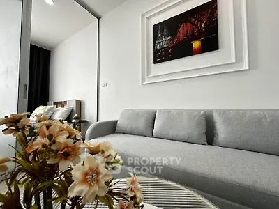Modern living room with stylish gray sofa and elegant wall art, featuring cozy bedroom view.