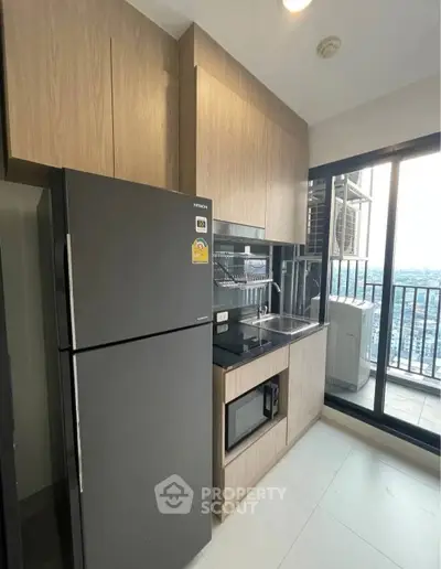 Modern kitchen with sleek appliances and balcony view in high-rise apartment