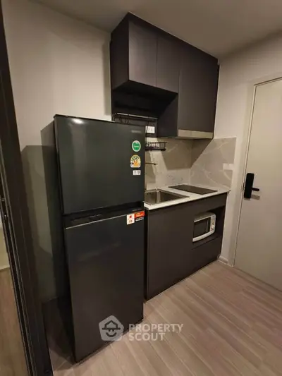 Modern compact kitchen with sleek black cabinets and appliances