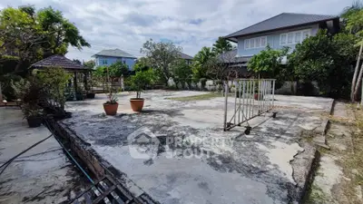 Spacious residential backyard with potential for landscaping, featuring a paved area and lush greenery.