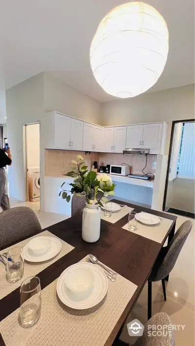 Modern kitchen with dining area featuring elegant table setting and contemporary lighting