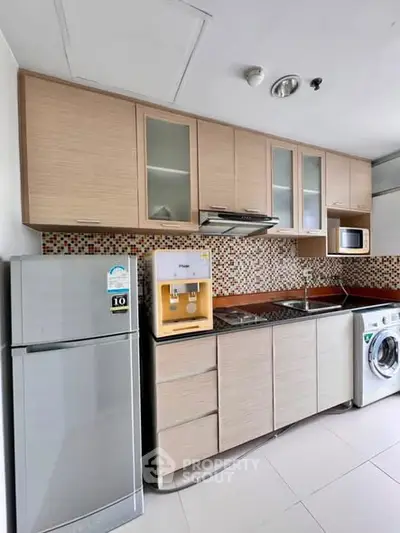 Modern kitchen with appliances including fridge, washing machine, and microwave in stylish apartment.