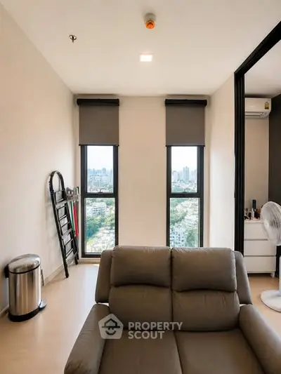 Modern living room with city view, featuring sleek furniture and large windows.