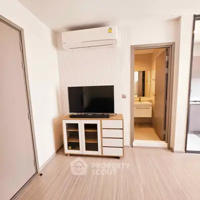 Modern living room with air conditioning and TV, adjacent to a bathroom, showcasing sleek design and functionality.