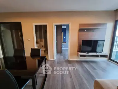Modern living room with sleek TV setup and dining area in stylish apartment