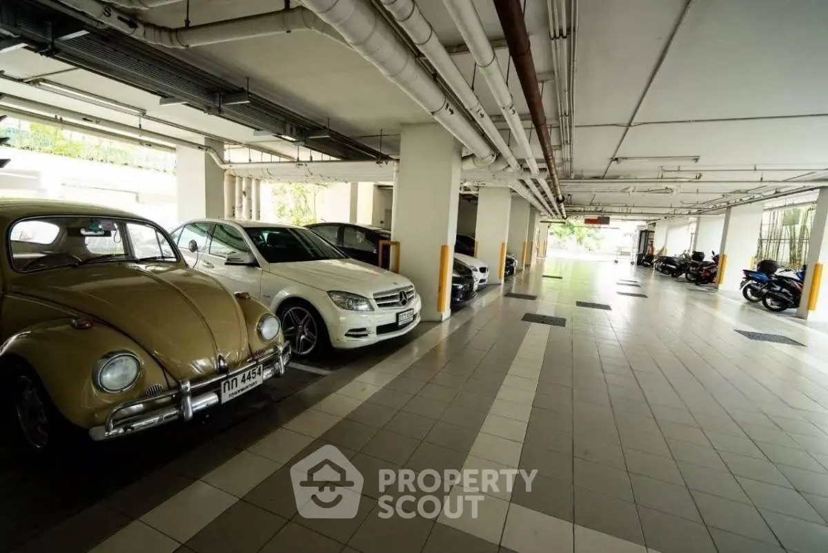 Spacious indoor parking area with classic and modern cars, ideal for urban living convenience.