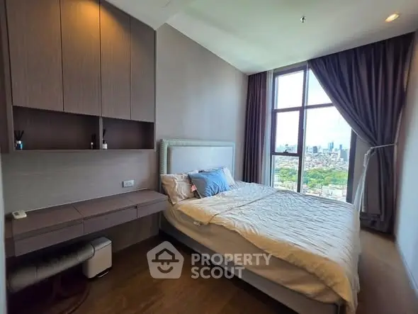 Modern bedroom with city view, featuring sleek furniture and large window for natural light.