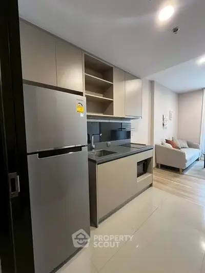 Modern kitchen with sleek cabinetry and stainless steel fridge in open layout apartment.