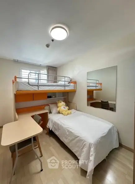 Cozy bedroom with bunk bed and study desk, ideal for students or small families.