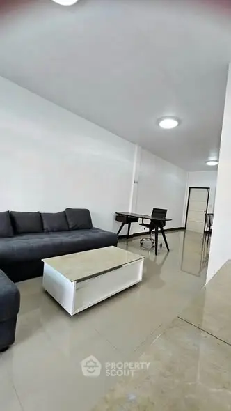 Modern living room with sleek furniture and glossy tiled flooring in a minimalist apartment.