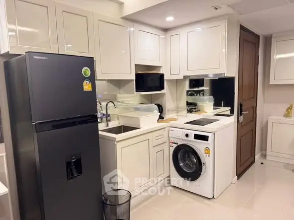 Modern kitchen with sleek appliances and washing machine in compact layout.