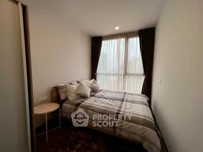 Cozy bedroom with large window and city view, featuring modern decor and plush bedding.