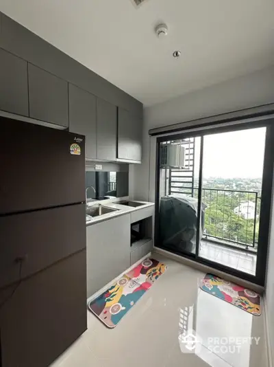 Modern kitchen with sleek cabinetry and balcony view, featuring a spacious fridge and stylish floor mats.